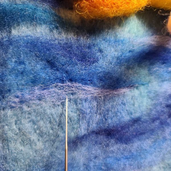 Follow along the length of the strip with your felting needle to secure the motion line in place, creating a wave or zig zap shape as you go.