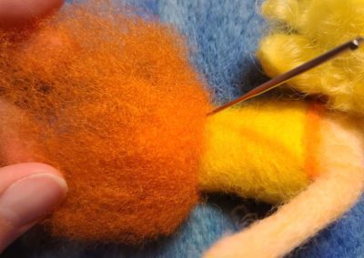 Gathering a puffy clump of wool fibers for the skirt, I secure the fibers in place at the waist, leaving the bottom hem of the skirt loose and fluffy.